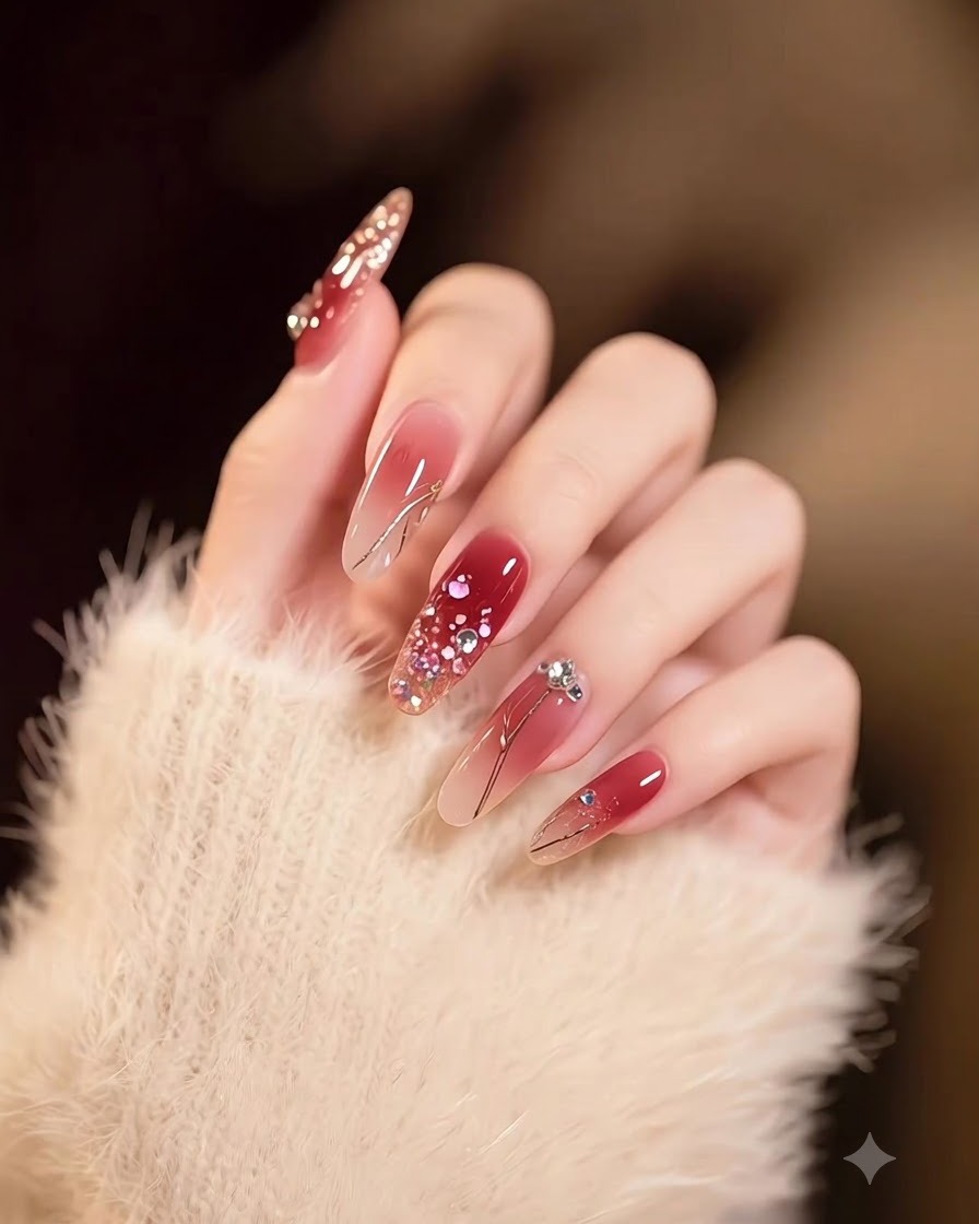 Main présentant des ongles carrés longs avec un dégradé fluide du nude au bourgogne foncé, décorés de flocons dorés.