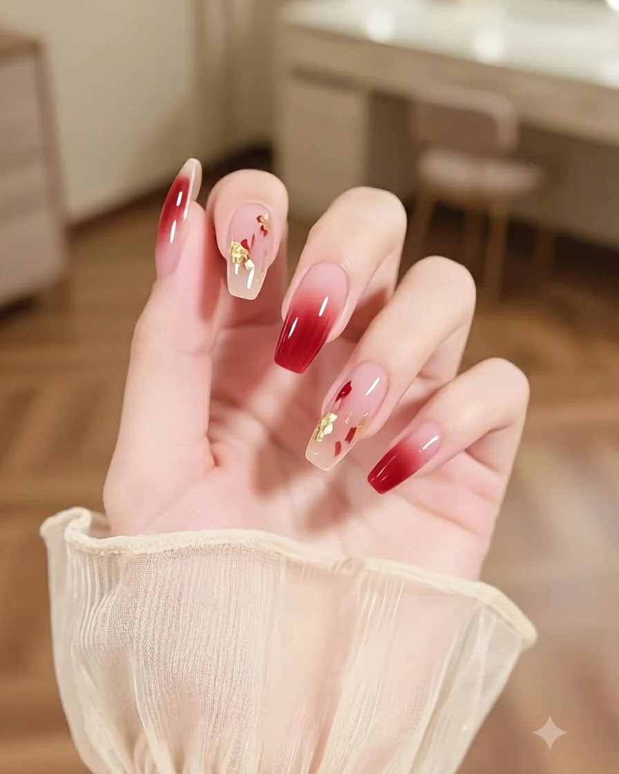 Gros plan dune main présentant un ongle accentué de coups de pinceau multicolores abstraits et de paillettes dorées à côté dongles ombré bourgogne.