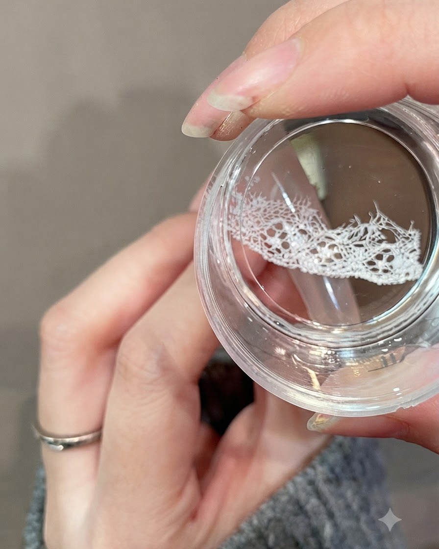 Un tampon clear jelly transférant un design de dentelle blanche délicate sur la partie supérieure dun ongle.