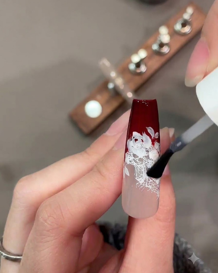 Un pinceau appliquant une couche de finition mate sur un design dongle en dentelle rouge foncé et blanche.
