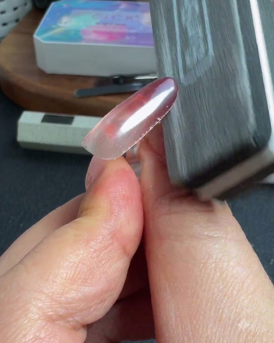 Une éponge ou une lime à ongle essuyant lexcès de poudre sur le bord dun ongle brillant.