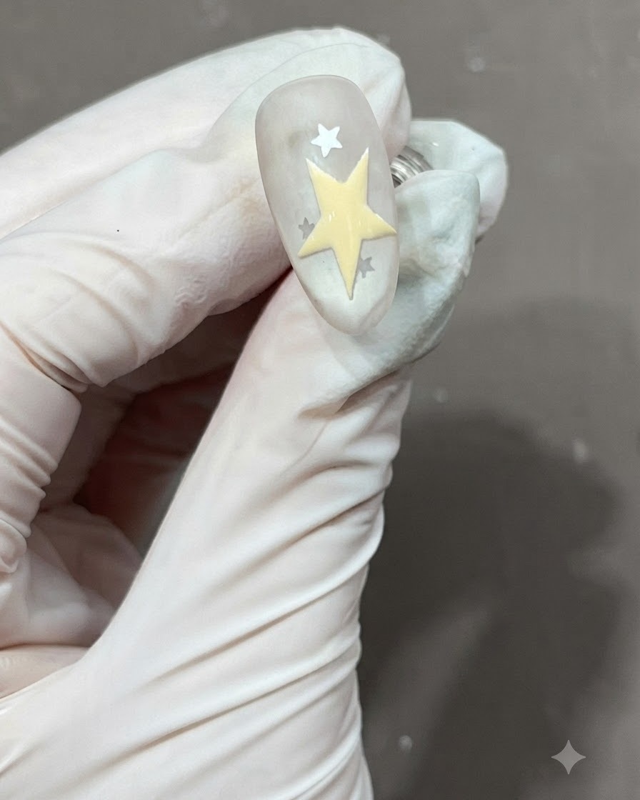 Étoile à cinq branches jaune fraîchement dessinée et remplie aux côtés dautres étoiles sur un ongle mat.