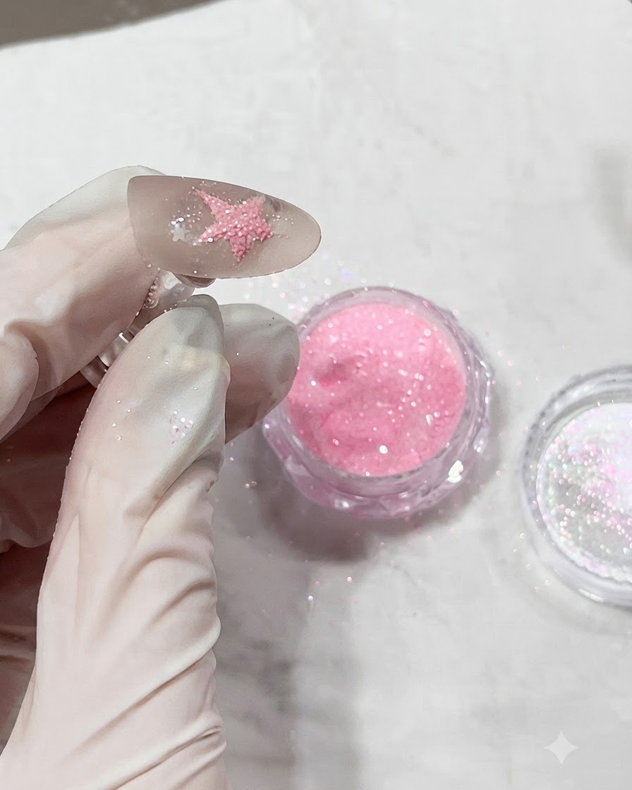 Ongle recouvert de poudre de diamant rose texturée juste avant dêtre catalysé sous une lampe.