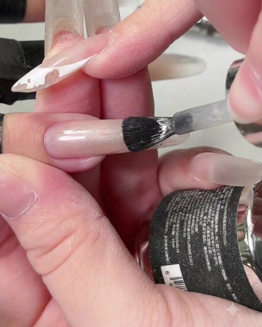 Un pinceau appliquant un gel cat-eye crystal transparent sur toute la longueur de longle.