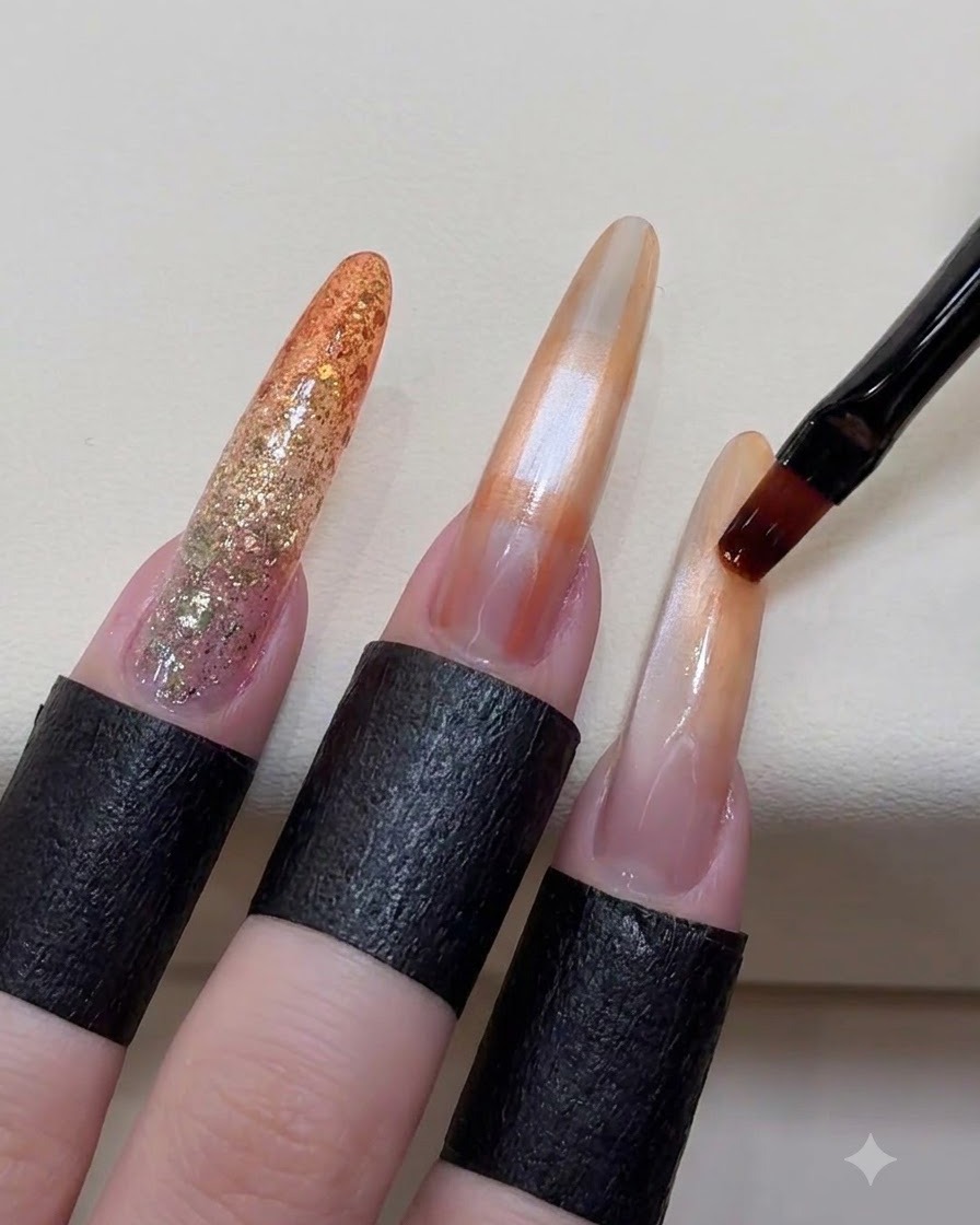 Un pinceau adoucissant doucement les contours des taches orange sur un ongle long.
