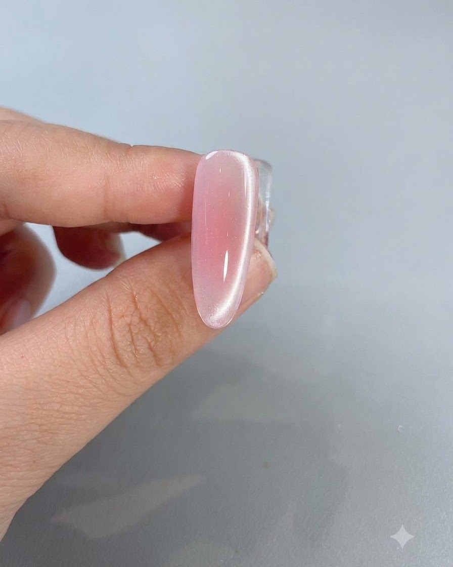 Gros plan dun ongle rose cat-eye terminé montrant une ligne de réflexion lumineuse vive longeant le côté.