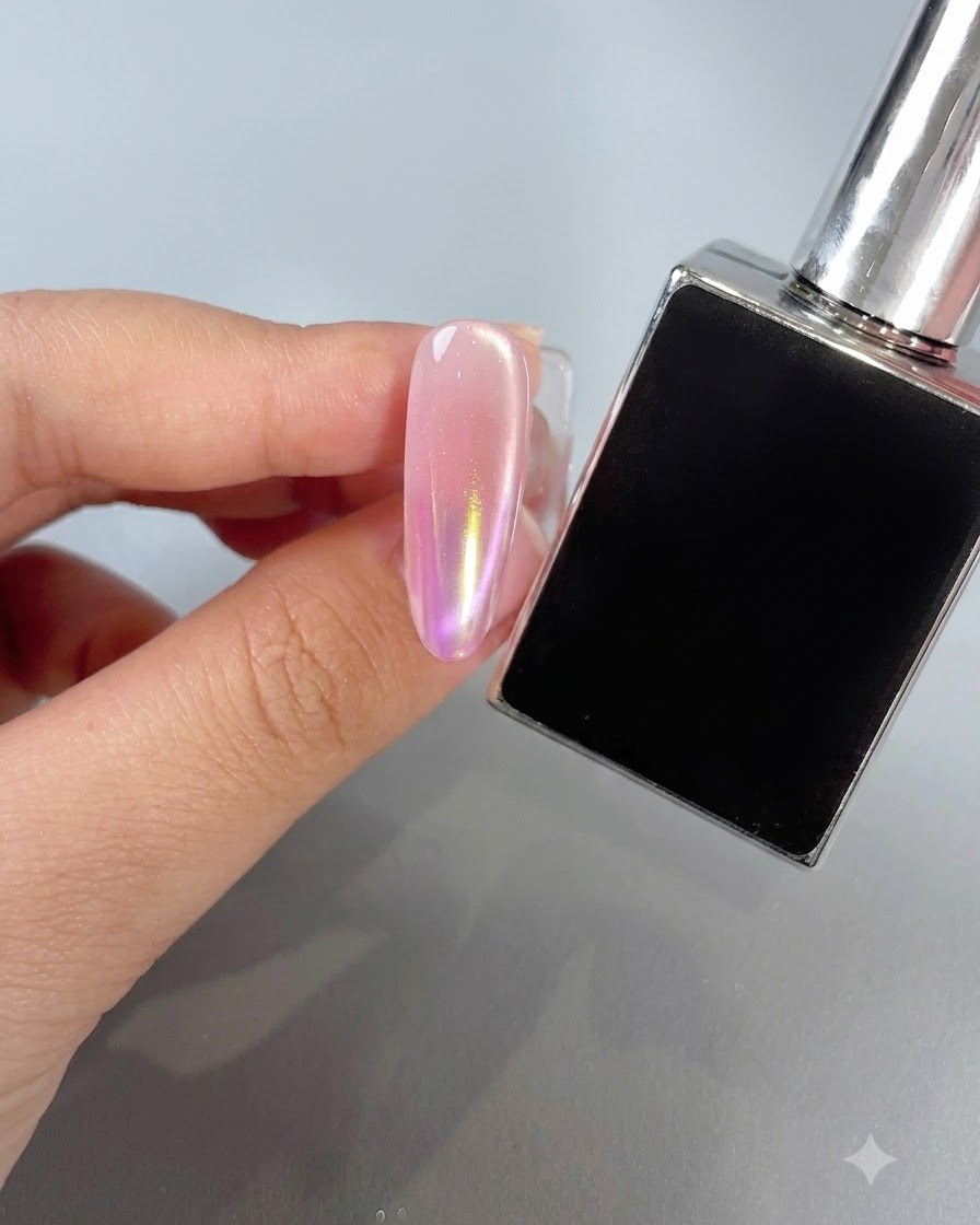 Un ongle manucuré présentant un dégradé de poudre aurora aux teintes chaudes sunset à côté dun flacon de vernis.