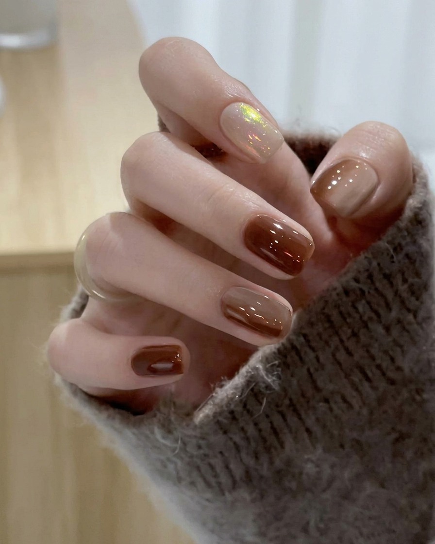 Un pinceau glissant du vernis gel nude translucide sur longle du majeur.