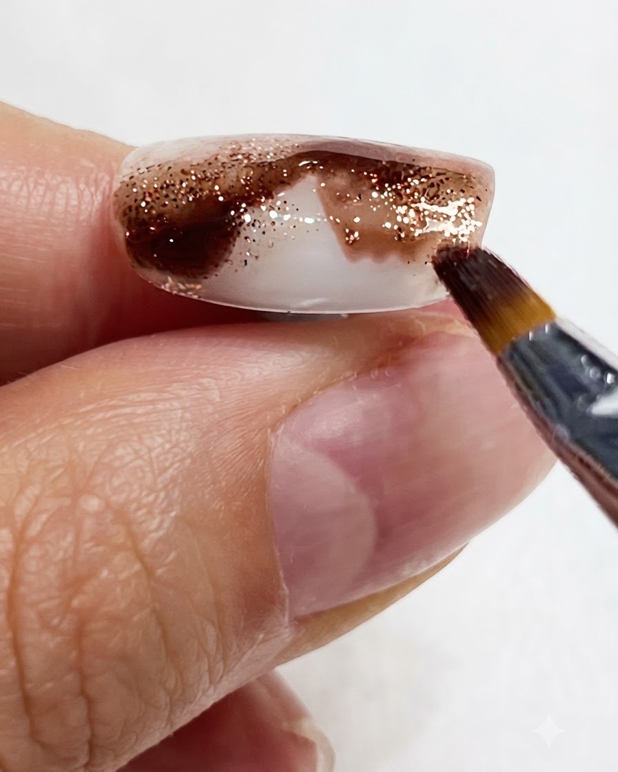 Gros plan montrant un pinceau fin étirant un pigment aquarelle ambré vers le bas de longle.