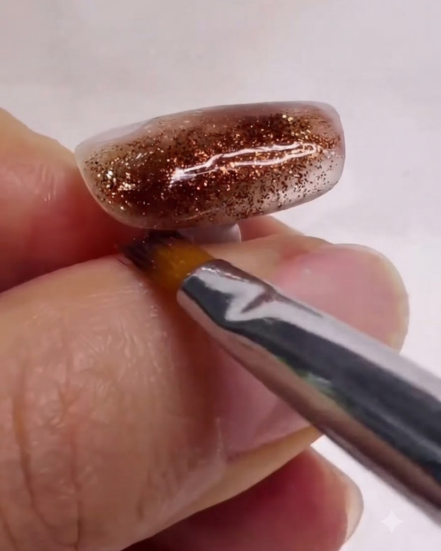 Un pinceau propre pour nail art lissant et mélangeant délicatement des couches de marbre blanc et marron sur un ongle texturé.
