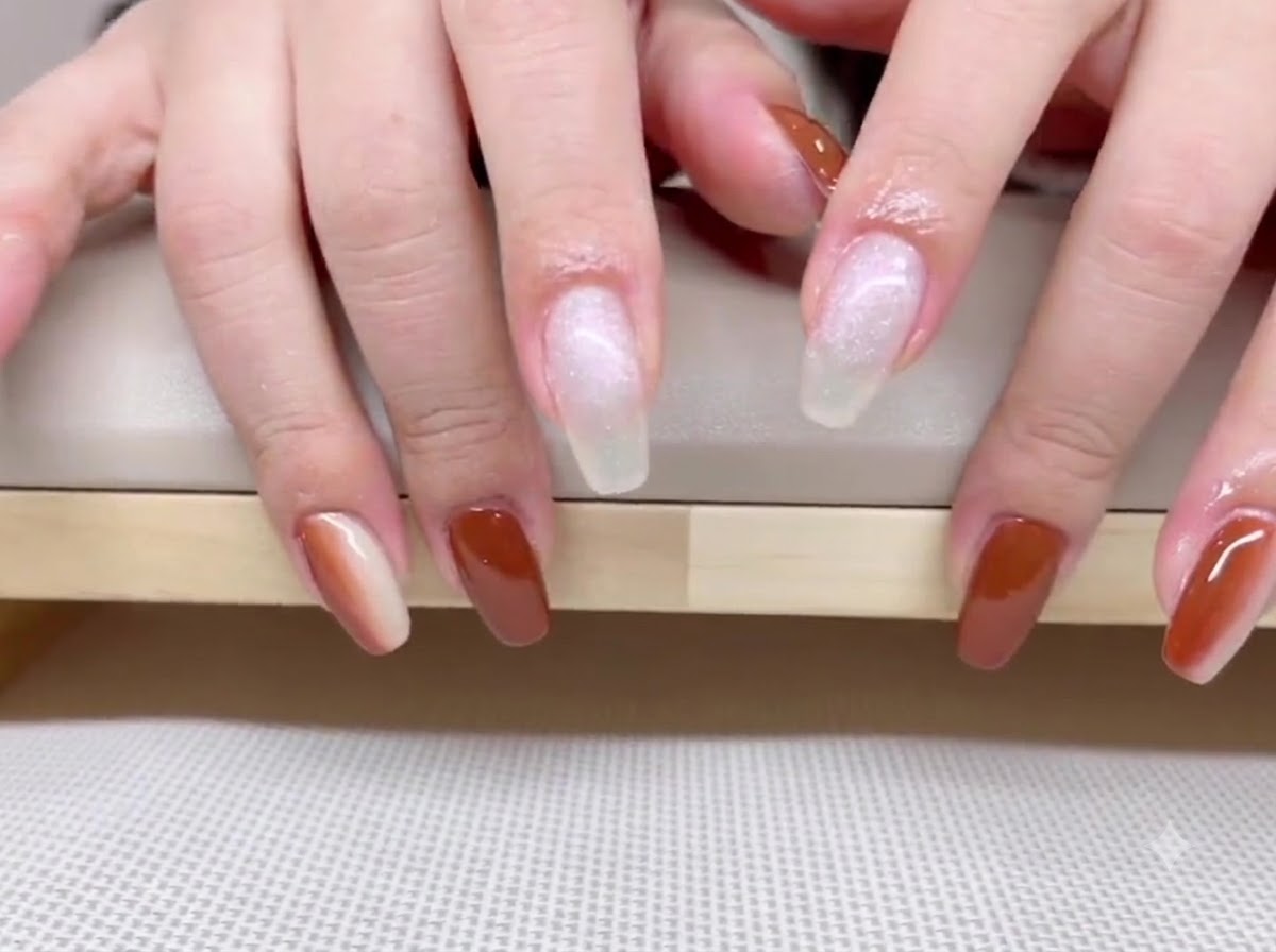Vue de mains montrant un riche vernis gel marron caramel sur le pouce, lannulaire et lauriculaire.