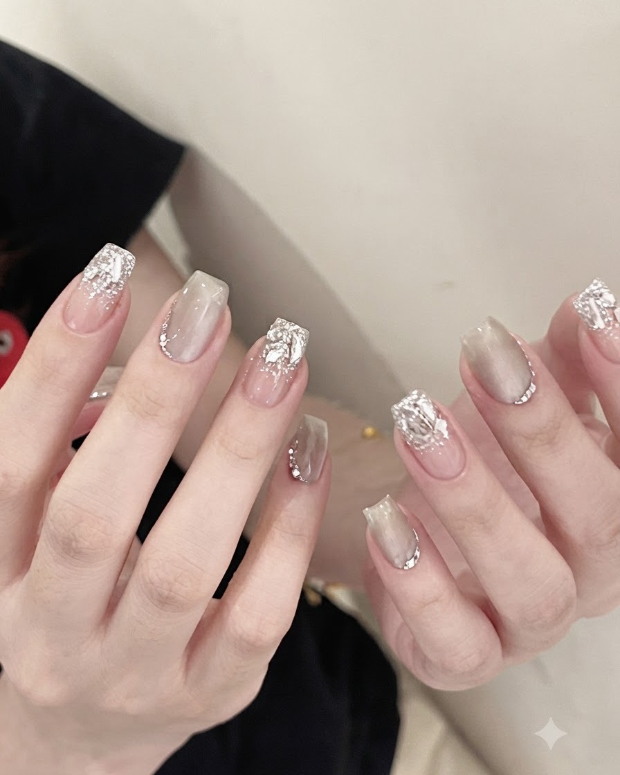 Une paire de pinces métalliques tenant un grand strass en cristal transparent étincelant et le plaçant à la base dun ongle manucuré.