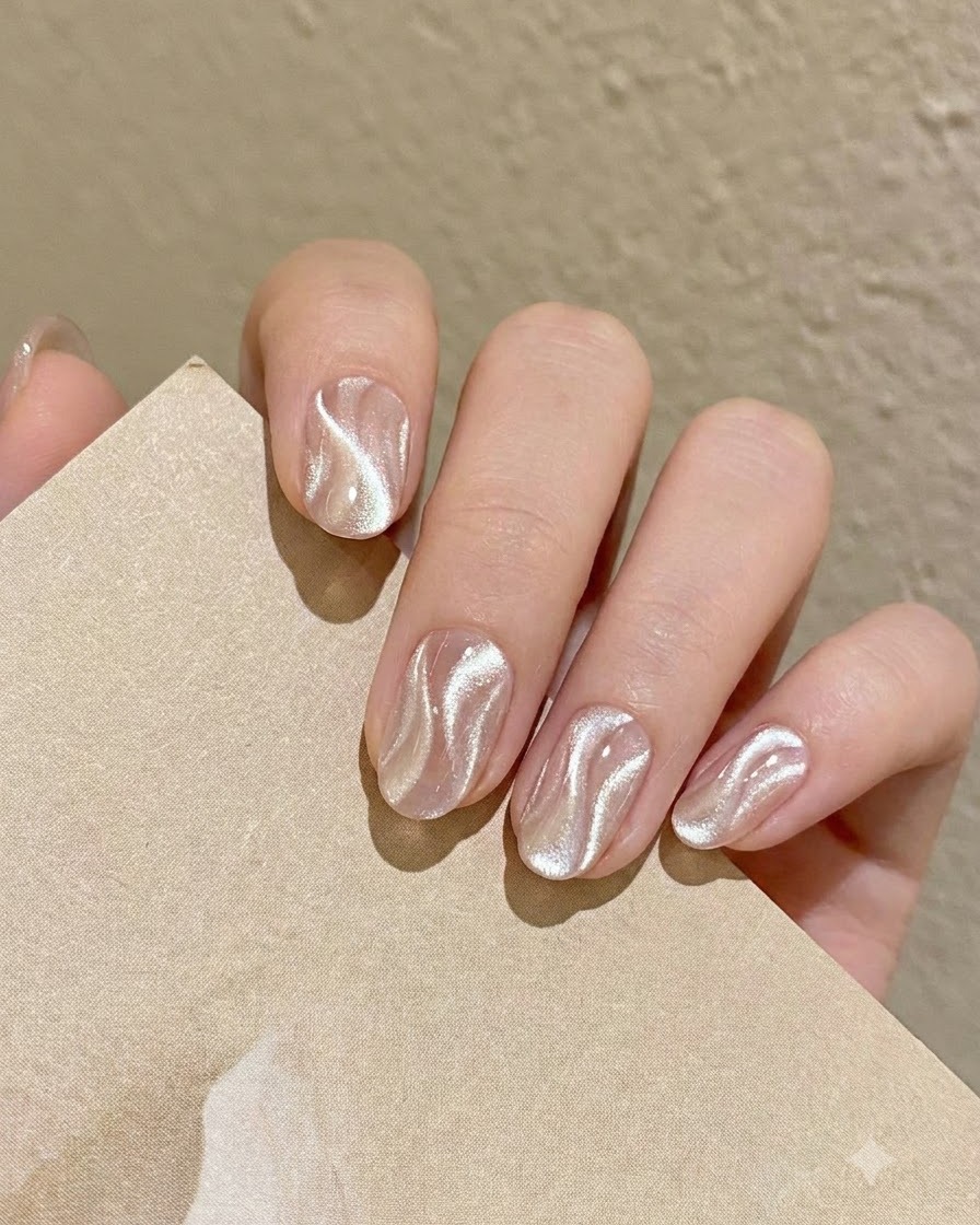 Un pinceau fin de nail art prélèvant une petite quantité de gel cat eye argenté scintillant sur la palette.