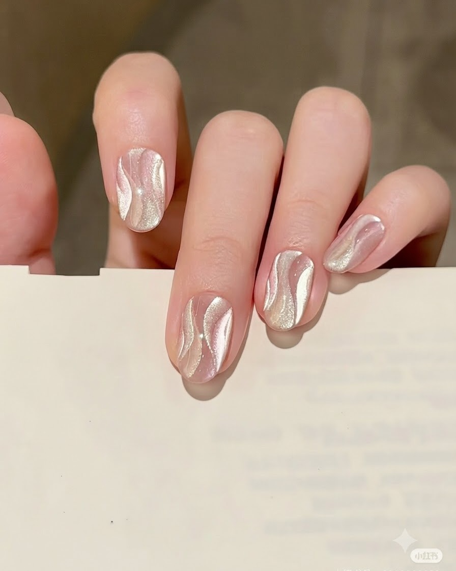 Un pinceau fin dessinant une forme de ruban élégante et incurvée avec le gel cat eye argenté sur la base nude.