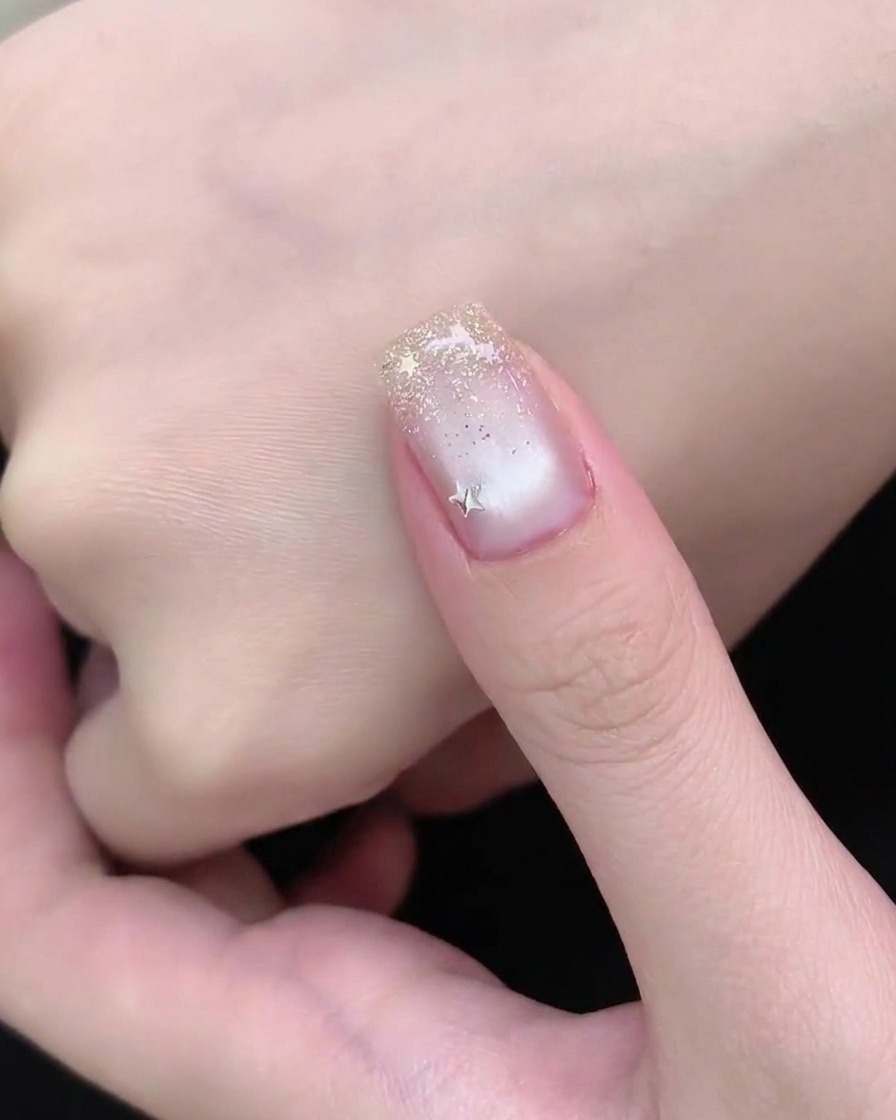Une main posée sous une lampe à ongles UV ou LED lors de la dernière étape de catalysation dune manucure.