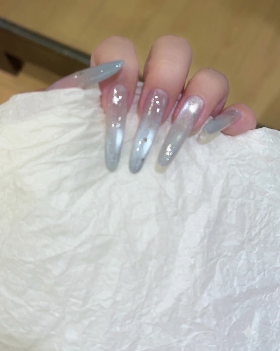 Une main tenant un mouchoir texturé blanc essuyant des ongles longs et translucides en gel.
