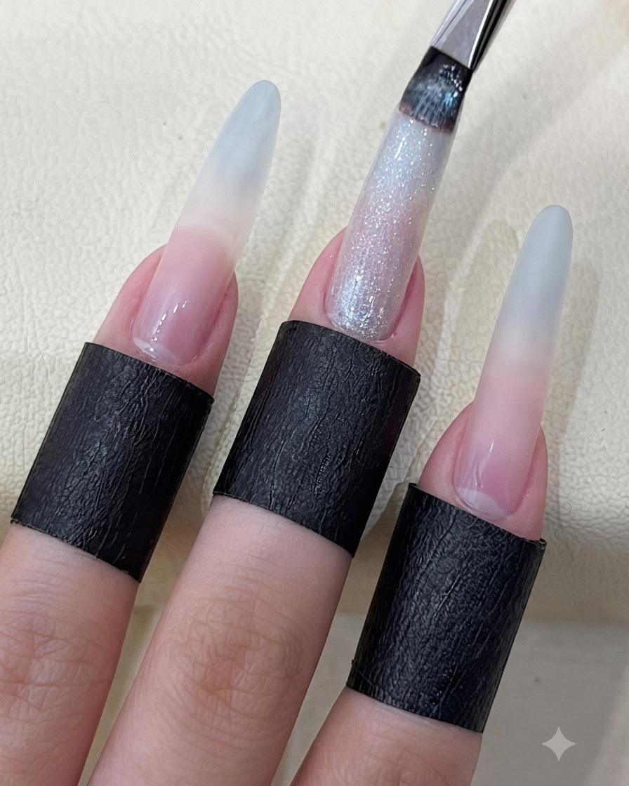 Un pinceau à ongles appliquant un gel cat eye étoilé scintillant sur un ongle long sculpté.