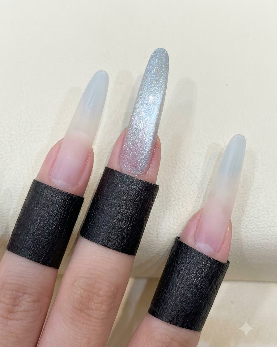 Une main montrant de longs ongles en amande avec le reflet cat eye en perle de verre terminé.