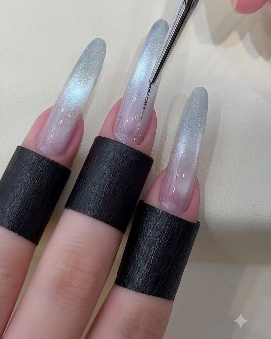 Un pinceau fin traçant une fine ligne argentée métallique au centre dun ongle cat eye étoilé.