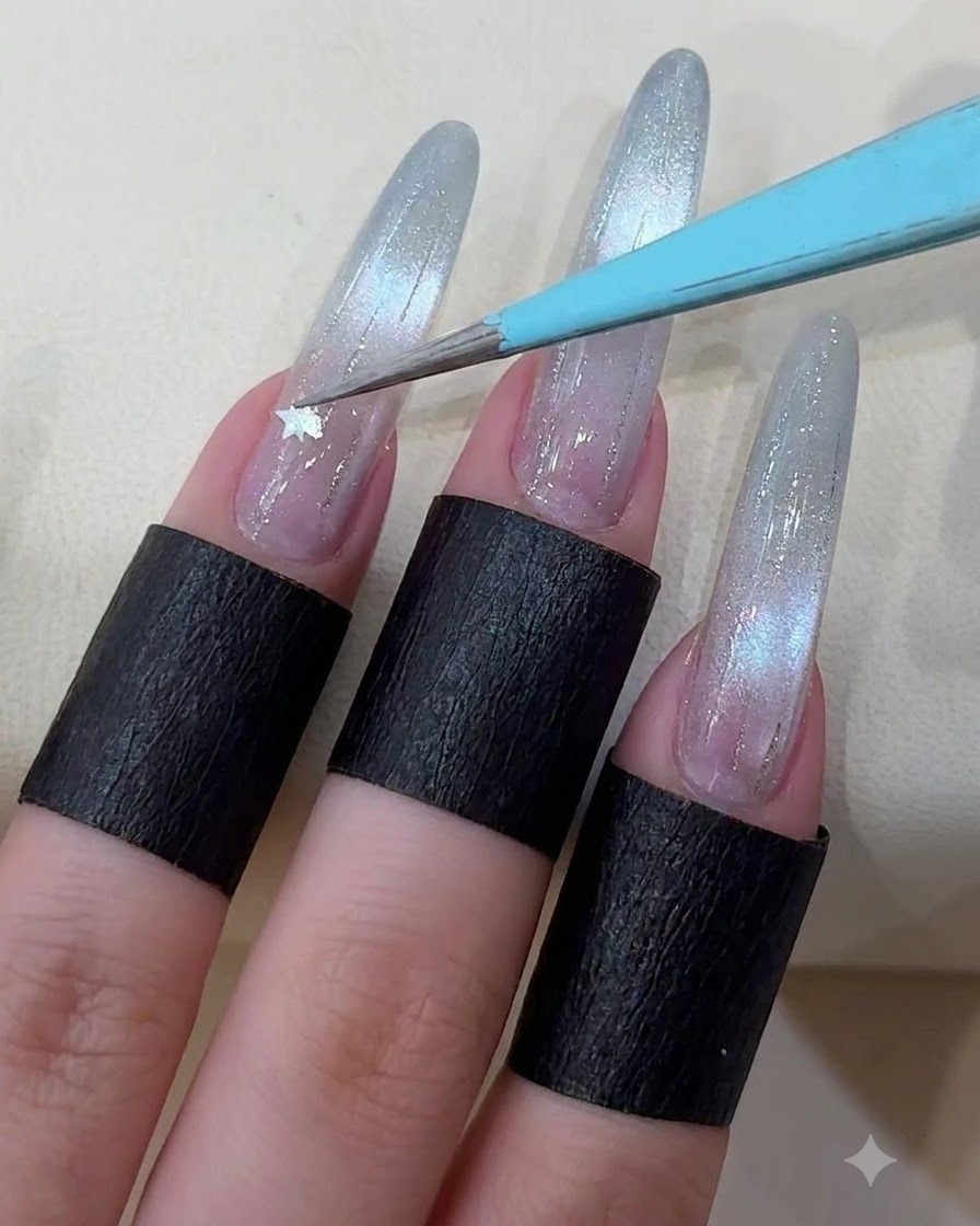 Une paire de pinces plaquant un petit sticker détoile métallique sur un ongle long décoré.