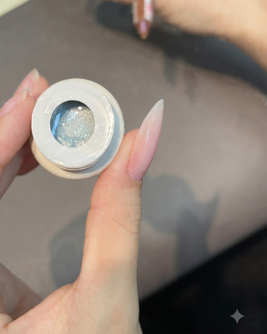 Un pinceau plat plongeant dans un pot ouvert de gel cat eye translucide numéro 49.