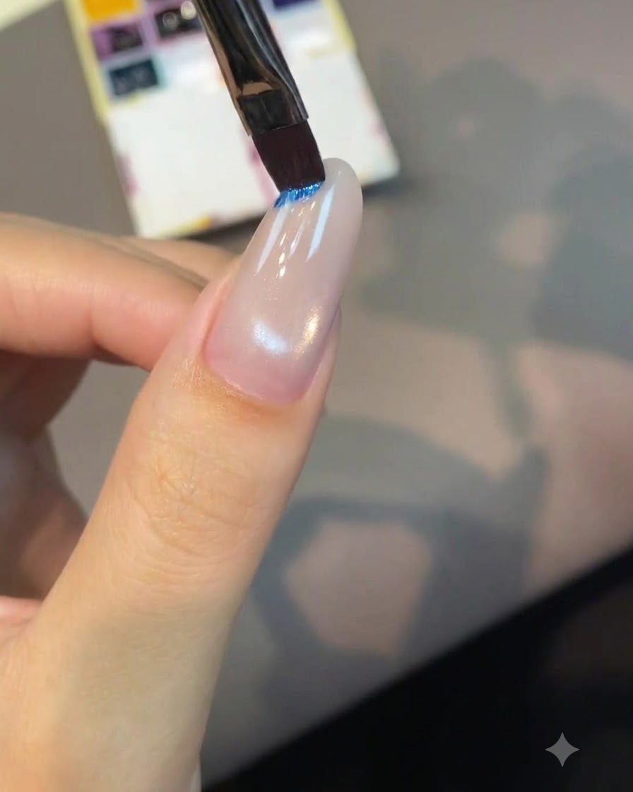 Un pinceau plat pour nail art trempant dans une palette de pigments bleu vif.