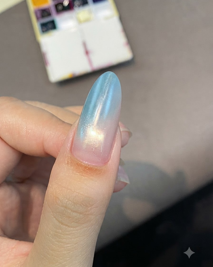 Un ongle en amande arborant un doux dégradé du bleu au rose, brillant sous léclairage de la catalyse.