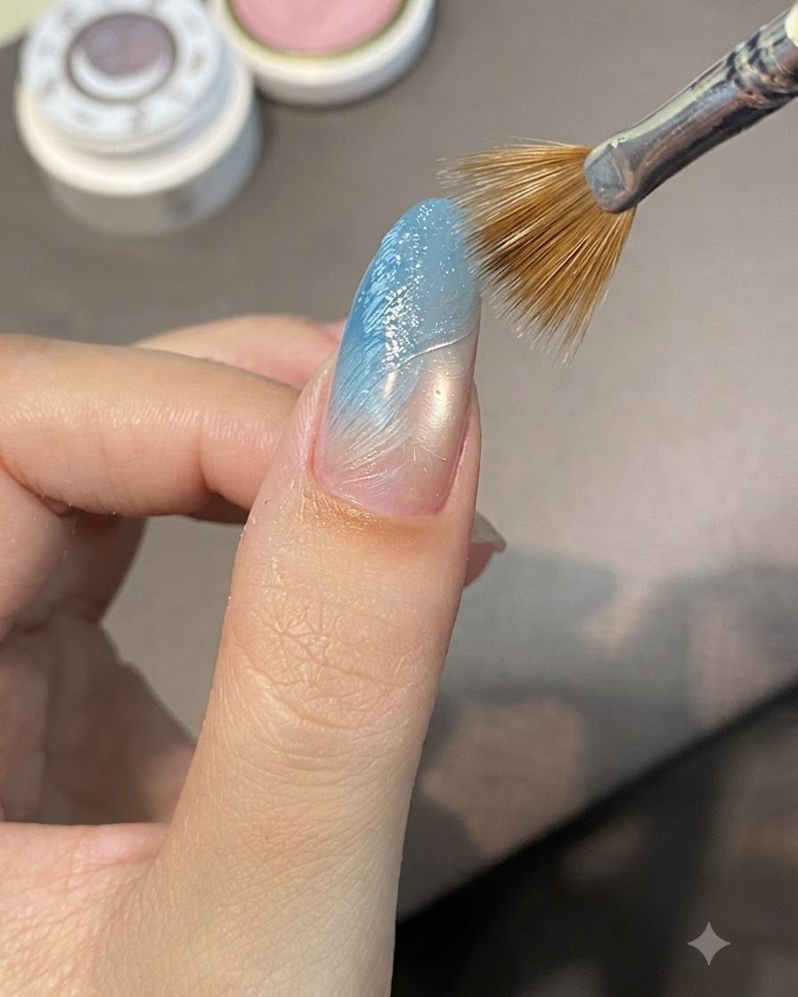 Un pinceau à bandes glissant en diagonale sur du gel de modelage humide sur un ongle à dégradé bleu pour former des crêtes en relief.