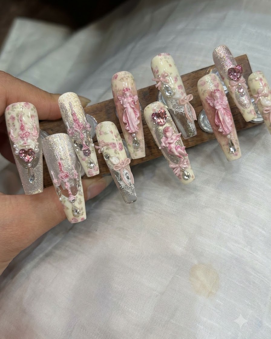 Une paire de brucelles plaçant un charme de nœud 3D et des strass sur un ongle fini.