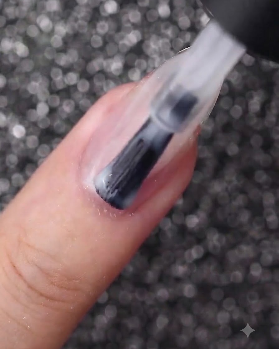 Un pinceau à ongles appliquant une couche lisse de vernis gel blanc laiteux sur un ongle de forme ovale.