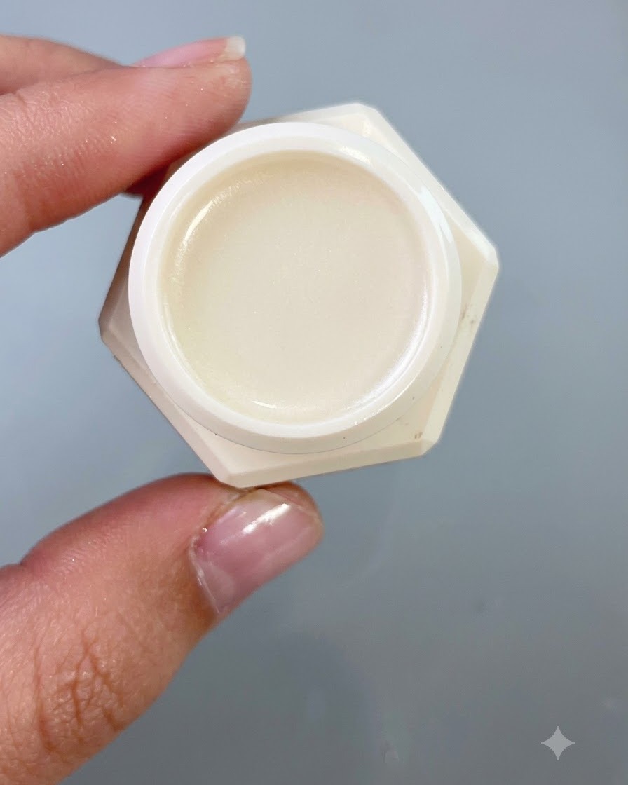 Gros plan dun petit pot contenant du gel de transfert, tenu sur un fond gris neutre.