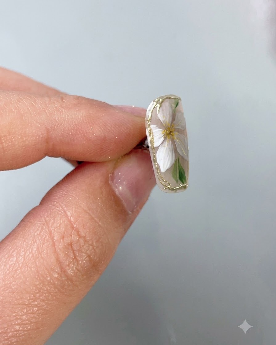 Un pinceau fin pour nail art appliquant un top coat protecteur transparent précisément sur une bordure délicate en chrome doré sur un ongle à base nude.