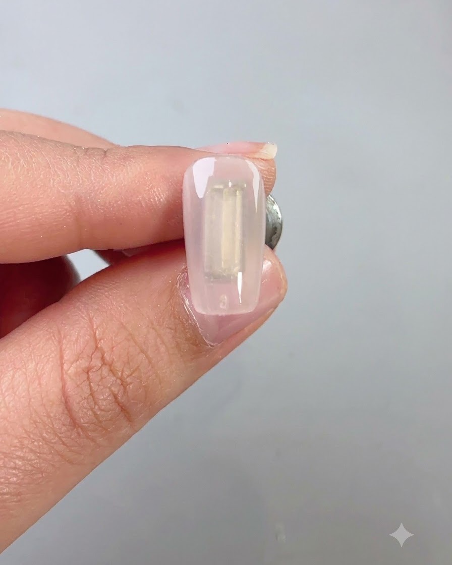 Un pinceau à ongles appliquant uniformément une couche de gel cat eye vert foncé wilderness sur un ongle.