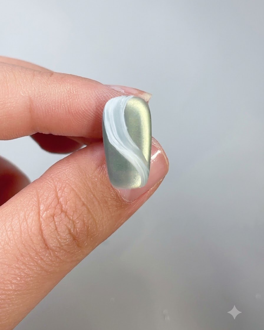 Gros plan dun ongle avec un design de nuage blanc recouvert dun top coat.