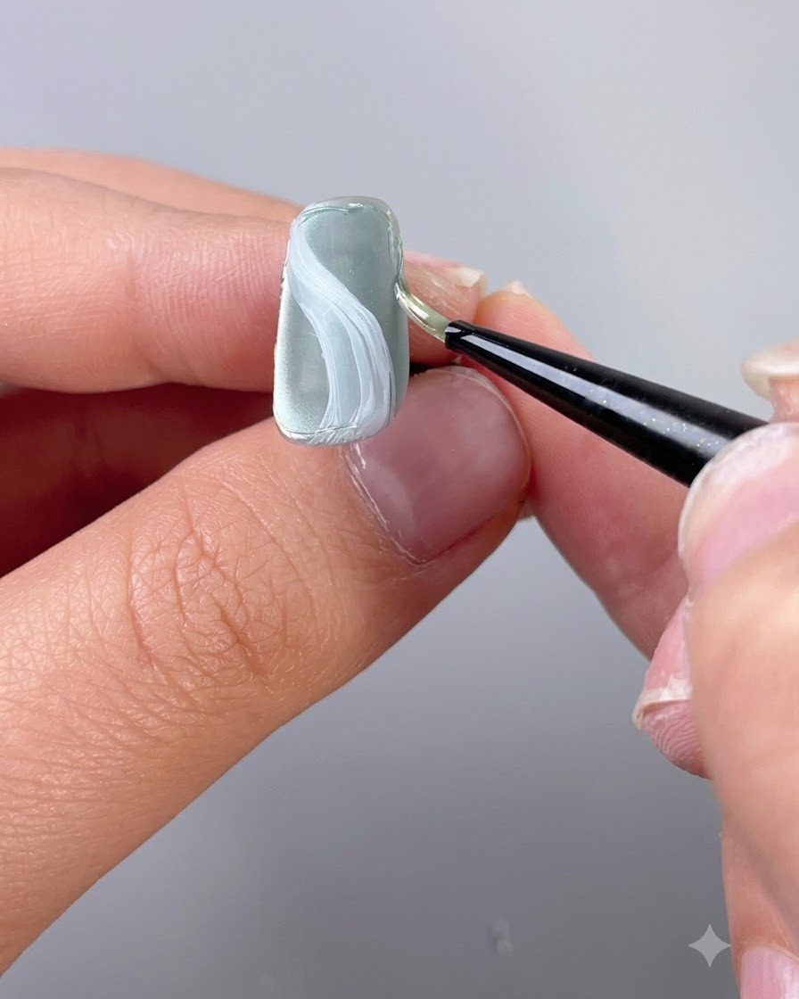 Un pinceau de détail fin appliquant du gel de modelage de texture le long du bord dun ongle.