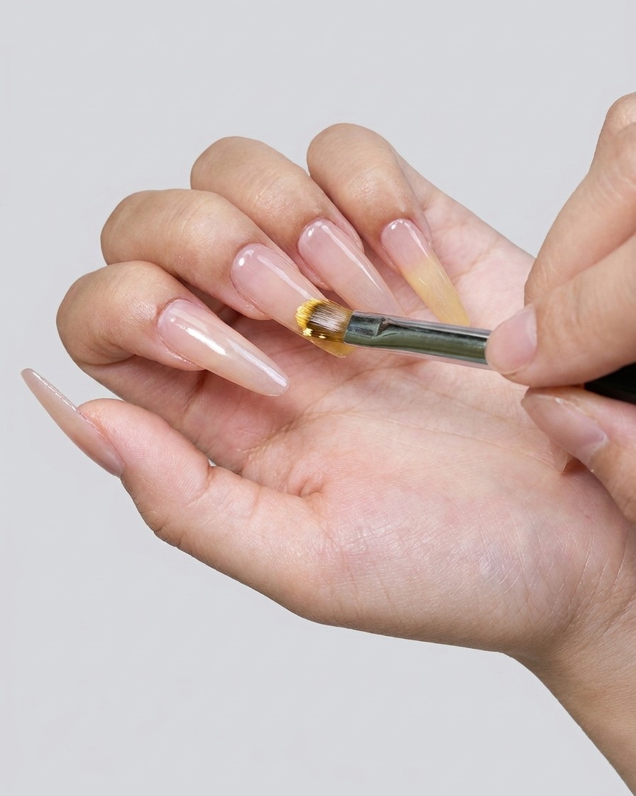 Gros plan dun pinceau appliquant du vernis gel jaune sur le bout de longle.