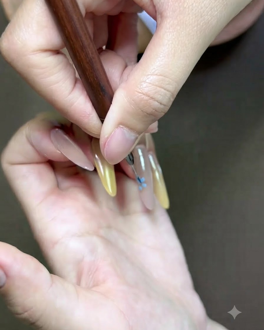 Gros plan détaillé dun pinceau de nail art fin ajoutant un accent floral rose sur longle.