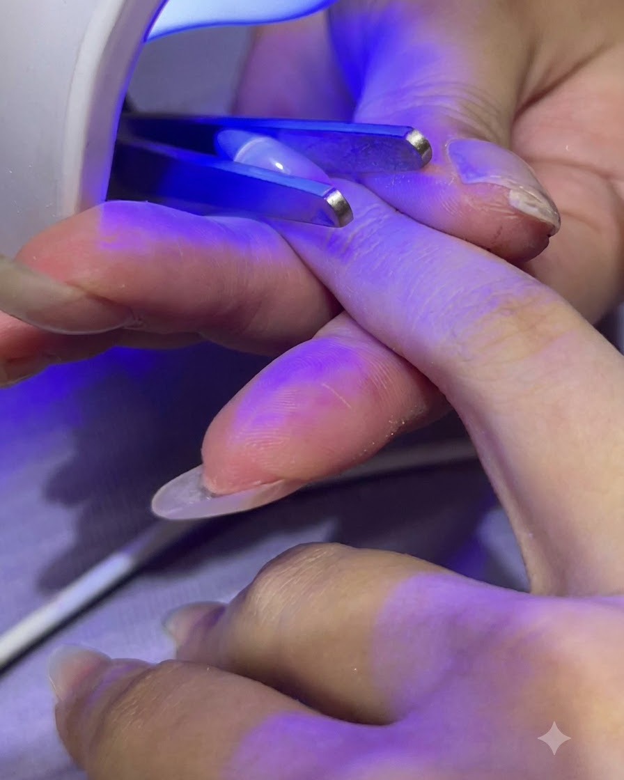 Une mini lampe UV/LED portative catalyse le gel de construction transparent sur un ongle.