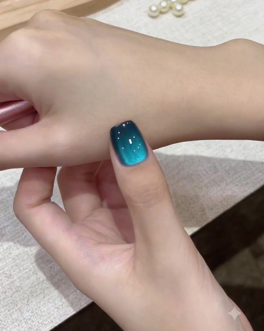 Une vue rapprochée dun seul ongle cat-eye galaxie sarcelle tenu contre le dos de la main.