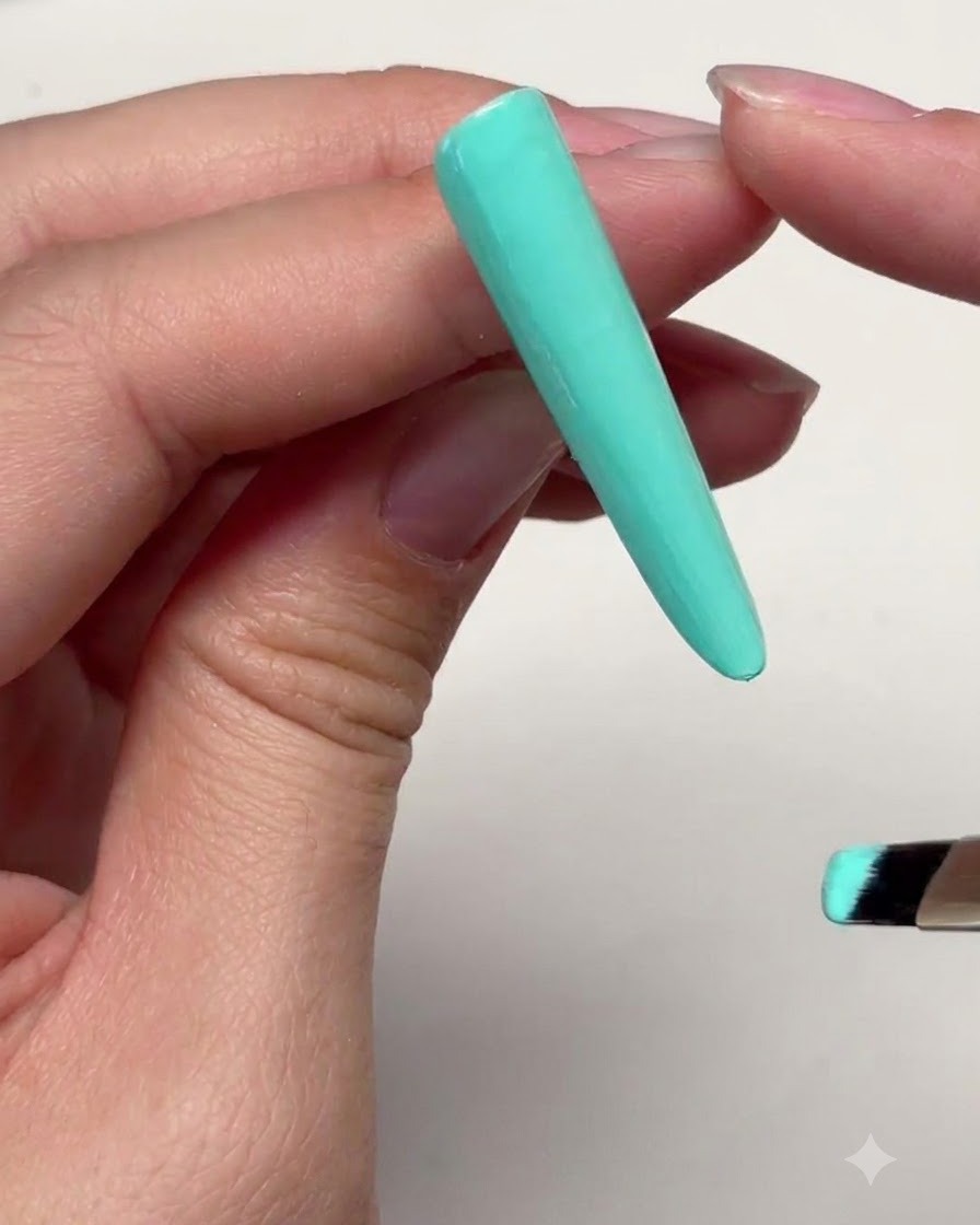 Une longue extension dongle vert menthe avec une fine couche de gel appliquée près de la zone supérieure des cuticules.