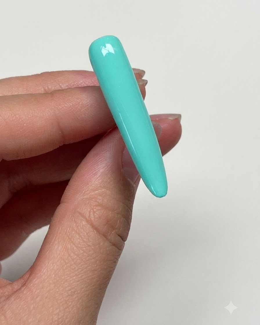 Une main essuyant la surface de longle vert menthe catalysé avec un disque imbibé dalcool pour éliminer leffet collant.