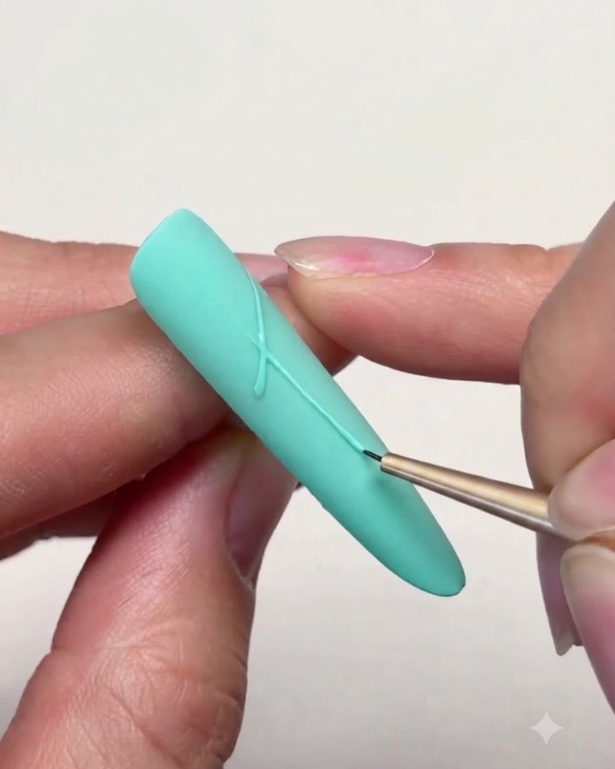 Un pinceau liner fin dessinant des traits précis pour relier les pointes dune étoile sur un ongle vert menthe.