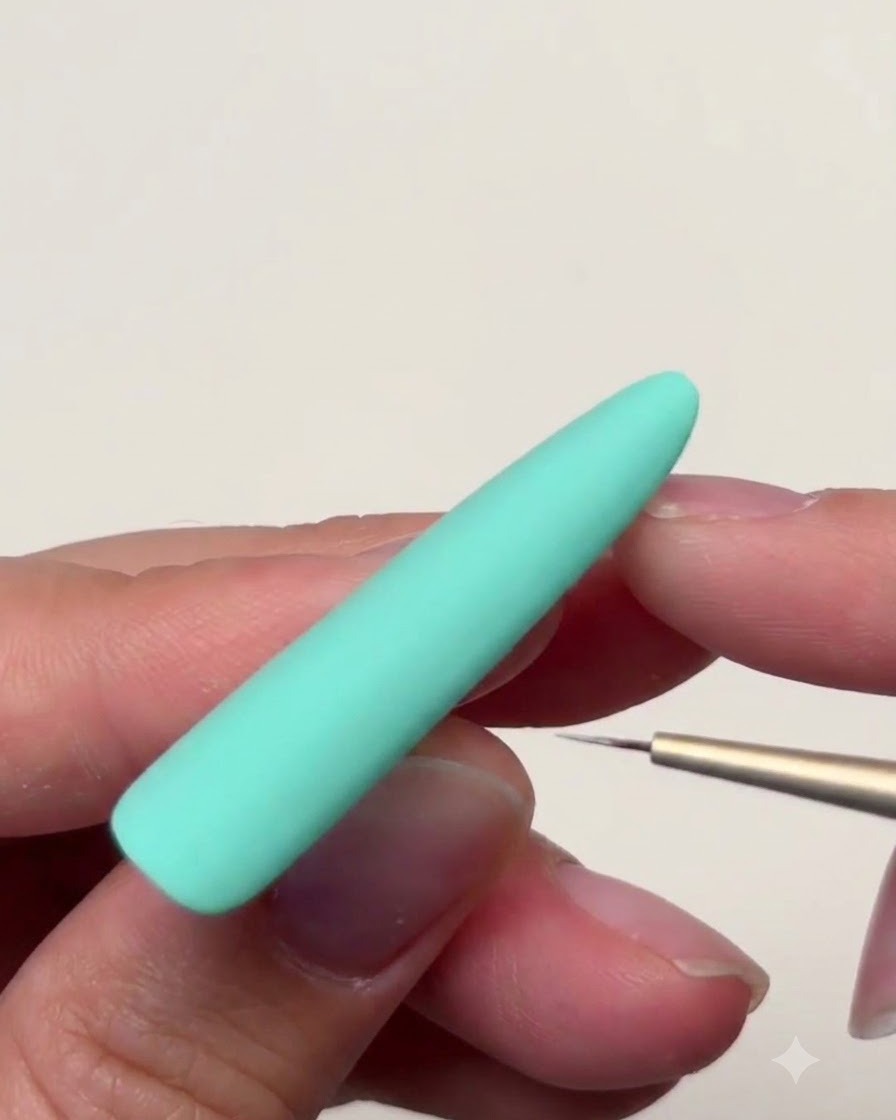 Vue rapprochée de la surface dun ongle vert menthe pendant que lon effile les pointes de létoile vers lextérieur avec un pinceau.