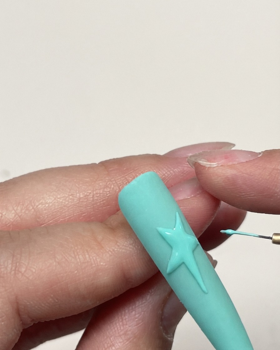Plan détaillé du contour dune étoile en gel achevée sur un ongle vert menthe avant lapplication de la texture.