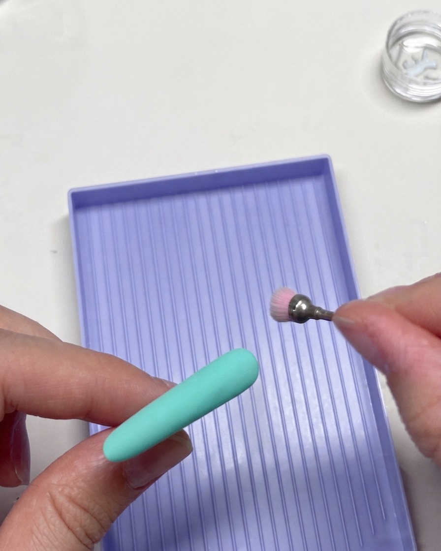 Un outil de fraisage rotatif affinant délicatement les bords de la pointe dun ongle vert menthe.