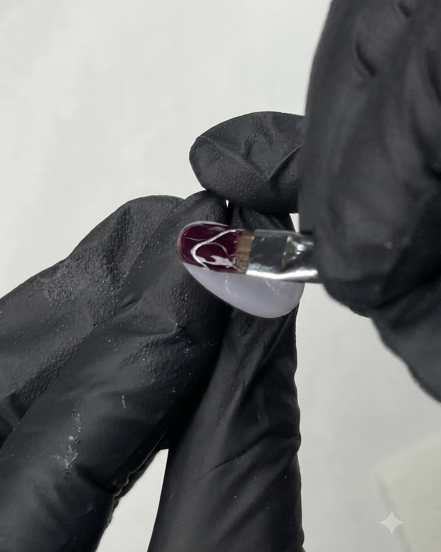 Un pinceau fin traçant de délicates lignes courbes blanches sur la surface dun ongle décoré.