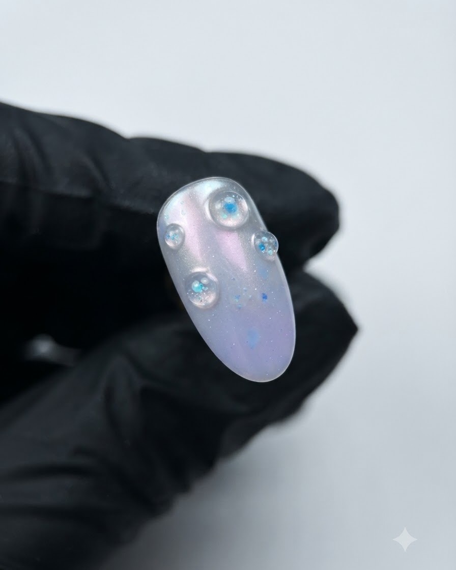 Un ongle terminé présentant des bulles de gel structurel cristal violet 3D en relief sur une base aurora.