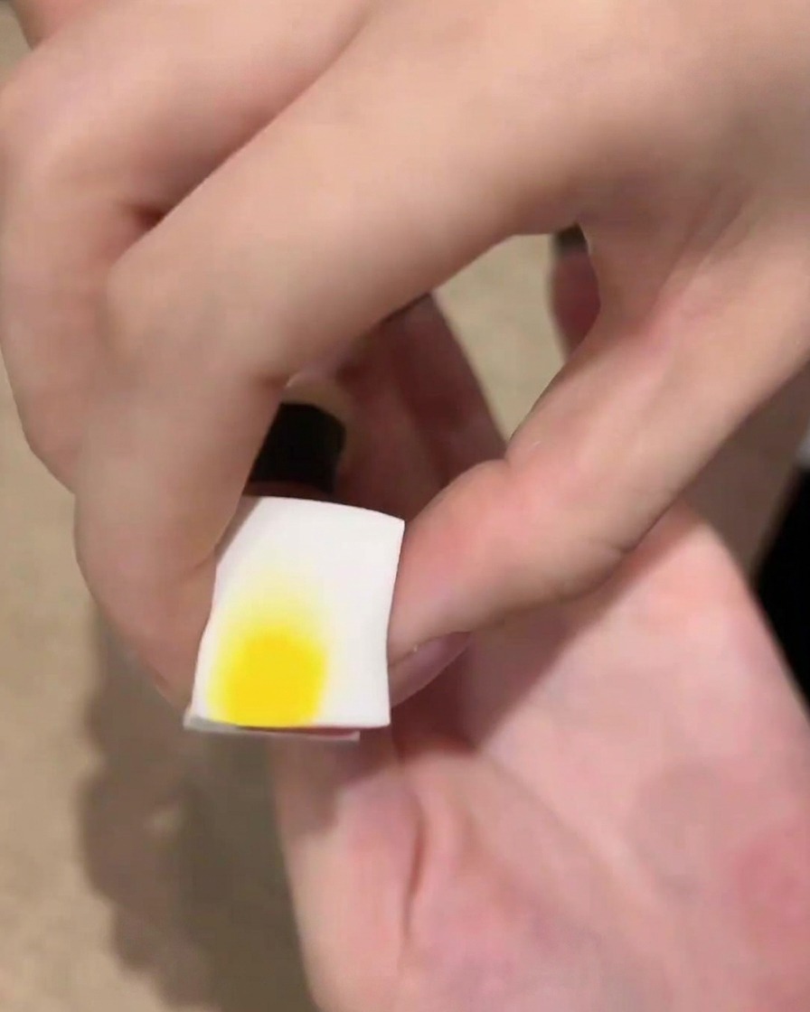 Une éponge cosmétique blanche contenant du vernis en gel noir près dun ongle, prête à tapoter pour un effet ombré.