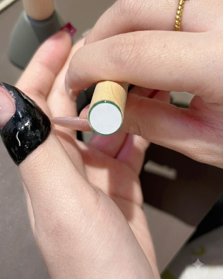 Un pinceau appliquant du vernis gel violet foncé sur le bord libre dun ongle à laspect naturel.