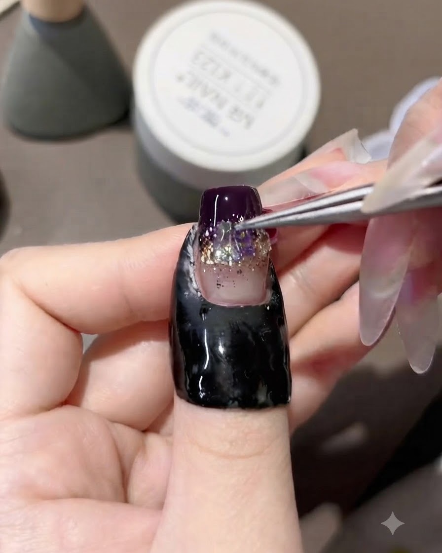 Une paire de brucelles plaquant des strass aurora iridescents au centre dun ongle en gel décoré.